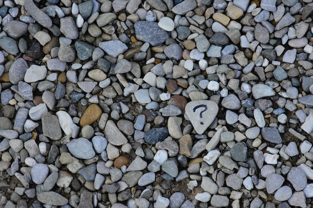 Question mark drawn on a single stone on the beach